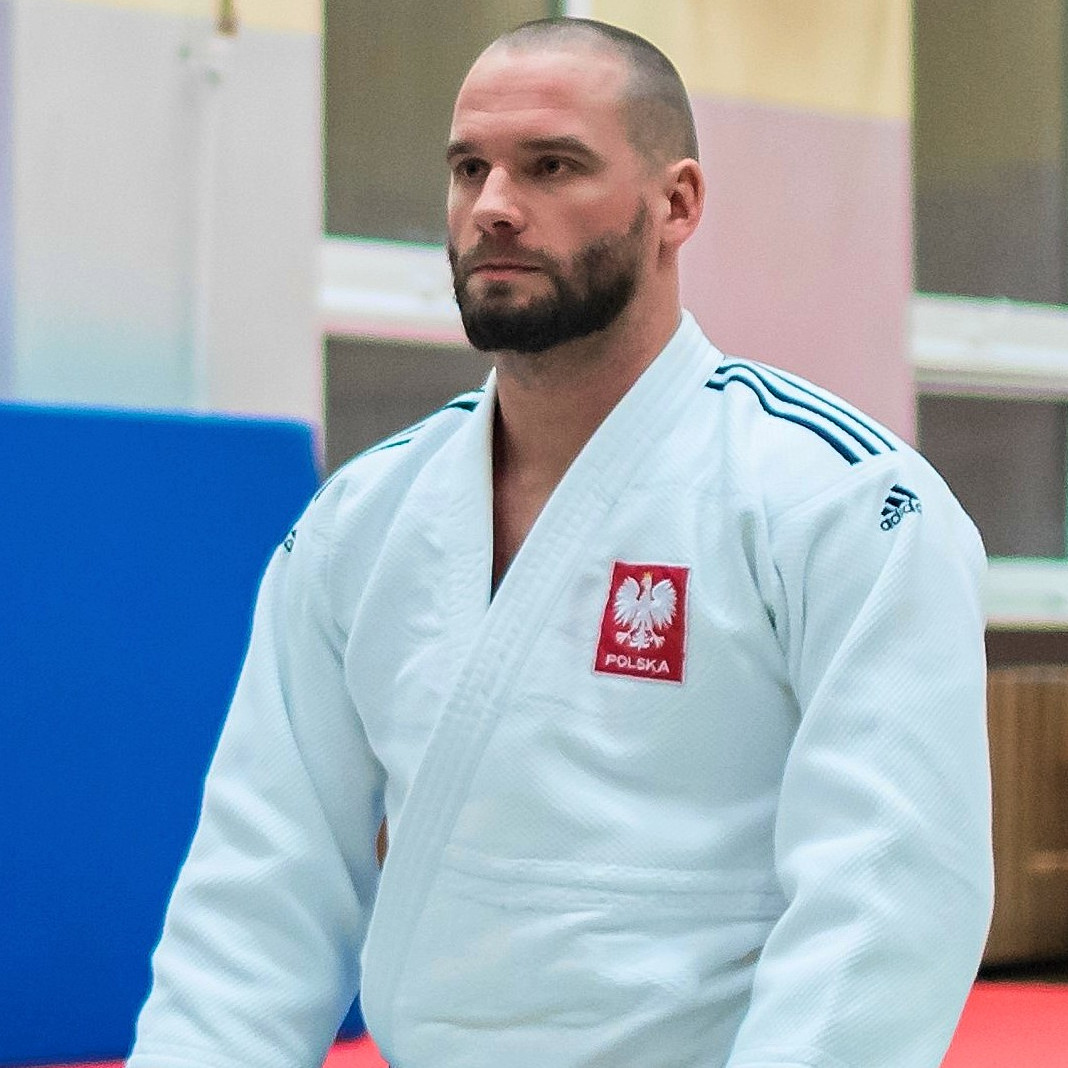 Trener Piotr Karolkowski w judodze z godłem Polski.